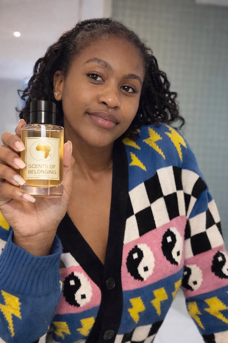 A customer in a patterned cardigan holds a bottle close