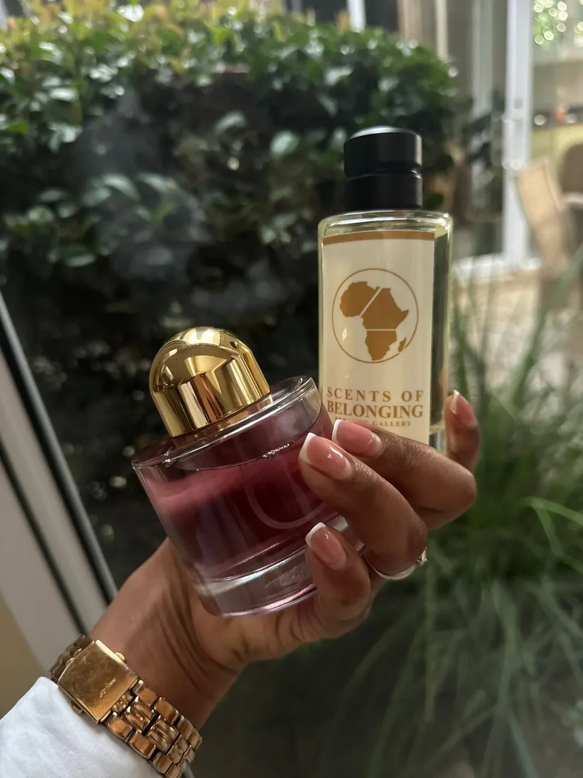 Two Scents of Belonging bottles held up in a garden